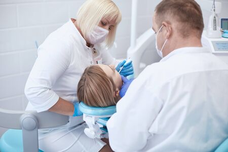 Doctor dentist treats teeth of a beautiful young girl patient. The girl on reception at the dentist. Doctor dentist treats tooth.の写真素材