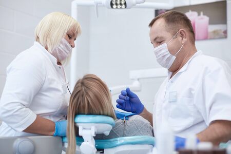 Doctor dentist treats teeth of a beautiful young girl patient. The girl on reception at the dentist. Doctor dentist treats tooth.の写真素材