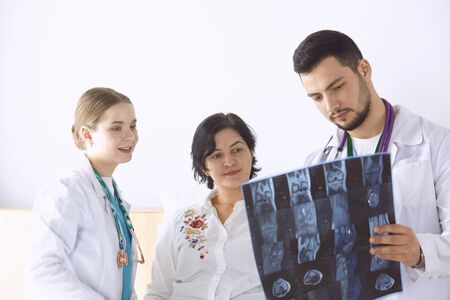 Doctor watching x-ray photography of elder womanの写真素材