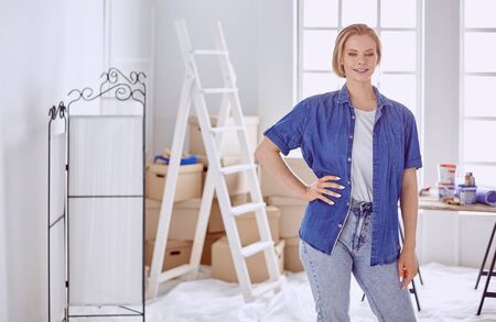 Beautiful young woman on a white wooden stepladder. Ready to repair the room. Women housework conceptの写真素材