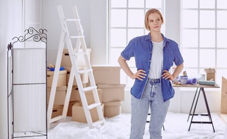 Beautiful young woman on a white wooden stepladder. Ready to repair the room. Women housework conceptの写真素材