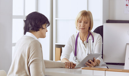 Doctor with computer and pregnant woman in doctors officeの写真素材