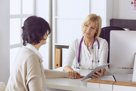 Doctor with computer and pregnant woman in doctors officeの写真素材