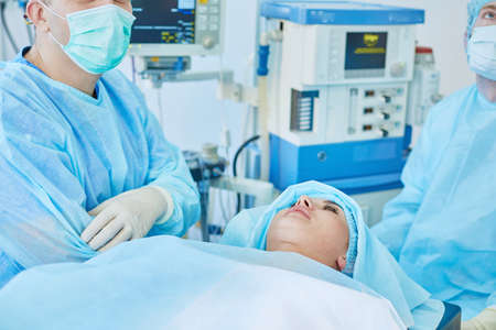 Several doctors surrounding patient on operation table during their work. Team surgeons at work in operating roomの写真素材