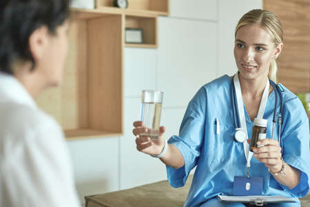 Beautiful smiling woman the doctor in a bottle of pill offers the patient. A panacea or life-saving antidepressant from a legal store prescribes vitamin health care for a healthy lifestyleの写真素材