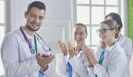 Happy medical team comprising male and female doctors smiling broadly and giving a thumbs up of success and hopeの写真素材