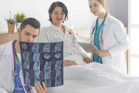 Doctor watching x-ray photography of elder womanの写真素材