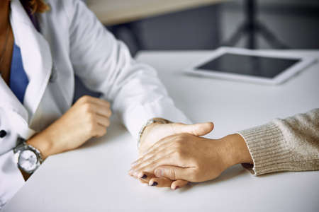 Woman doctor calms patient and holds handの写真素材