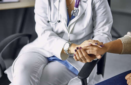 Woman doctor calms patient and holds handの写真素材