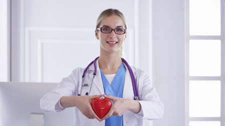 Doctor with stethoscope holding heart, isolated on white backgroundの写真素材