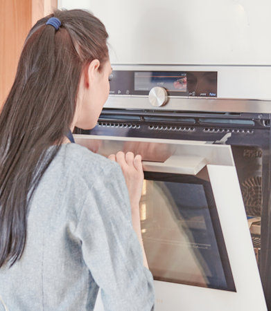 Beautiful woman in the kitchen, waiting with the front of the oの写真素材