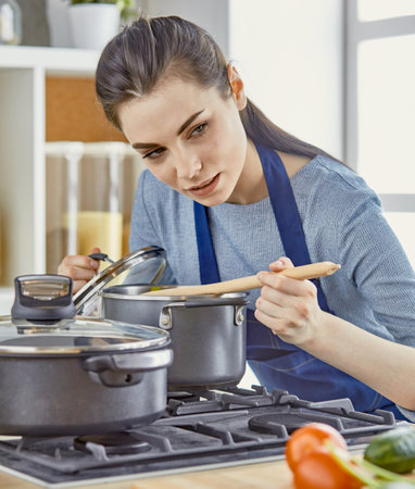 Beautiful woman in the kitchen, waiting with the front of the oの写真素材