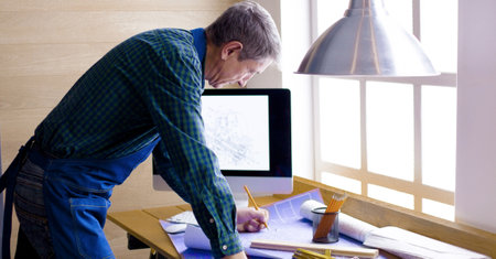 Engineer carpenter working on laptop and sketching projectの写真素材