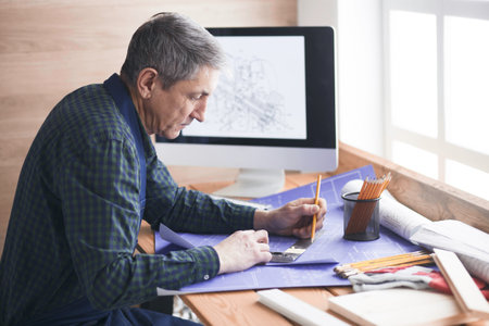 Engineer carpenter working on laptop and sketching projectの写真素材