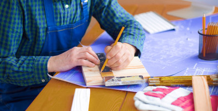 Engineer carpenter working on laptop and sketching projectの写真素材