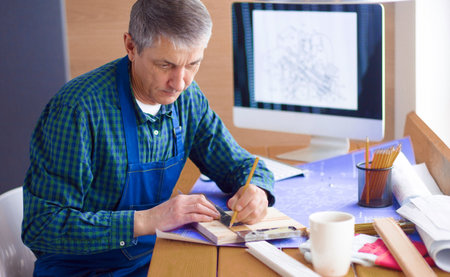 Engineer carpenter working on laptop and sketching projectの写真素材