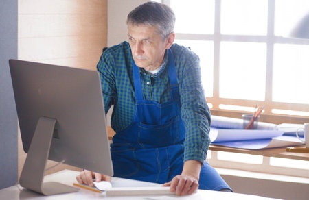Engineer carpenter working on laptop and sketching projectの写真素材