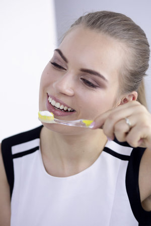 Smiling young woman with healthy teeth brushing her teethの写真素材