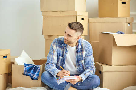 Handsome man with boxes in the new apartment after movingの写真素材
