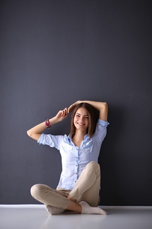 Young woman sitting on the floor near dark wallの写真素材