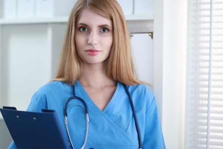 Portrait of woman doctor with folder at hospital corridorの写真素材