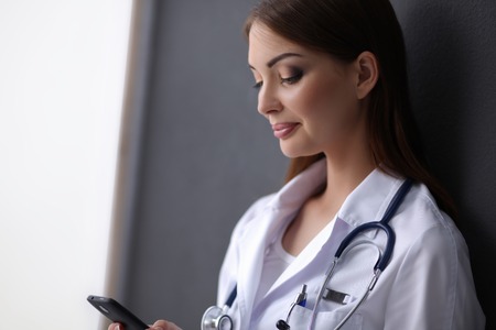 Young woman doctor sitting on the floor with your phoneの写真素材