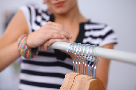 Beautiful young stylist near rack with hangersの写真素材