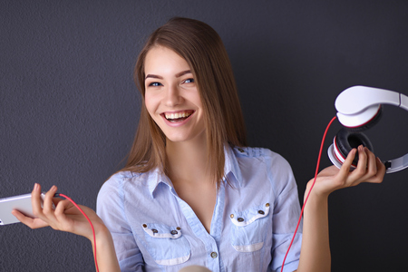 Smiling girl with headphones isolated on grey の写真素材