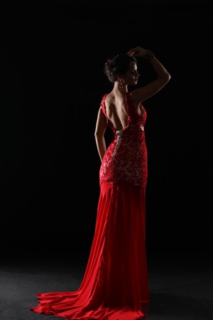 Young beauty woman in red dress. Isolated on black backgroundの写真素材