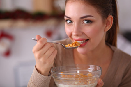 Smiling attractive woman having breakfast in kitchen interiorの写真素材