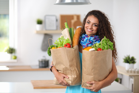 Young woman holding grocery shopping bag with vegetables Standing in the kitchen.の写真素材