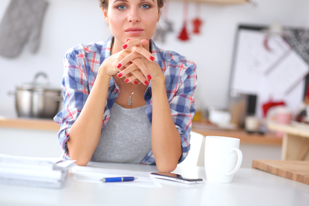 Smiling woman with cup of coffee and newspaper in the kitchenの写真素材