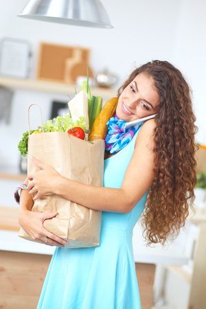Young woman holding grocery shopping bag with vegetables Standing in the kitchen.の写真素材