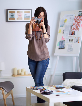 Young woman watching footage on film, standing near windowの写真素材