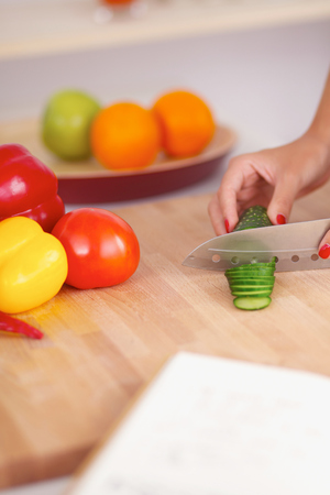Smiling woman preparing salad in the kitchen, isolatedの写真素材