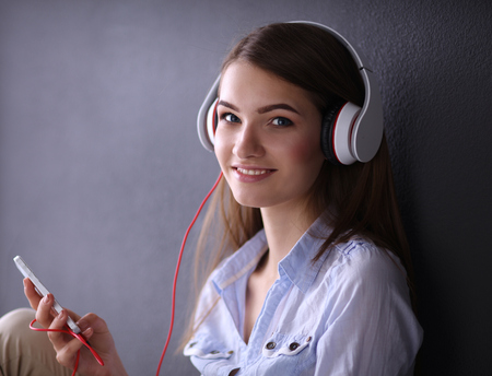 Smiling girl with headphones sitting on the floor near wallの写真素材