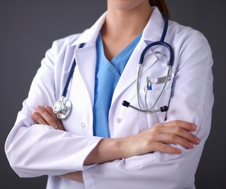 Young doctor woman with stethoscope standing near grey wallの写真素材