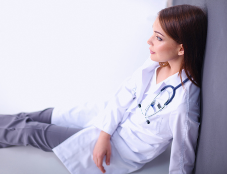 Young woman doctor sitting on the floorの写真素材