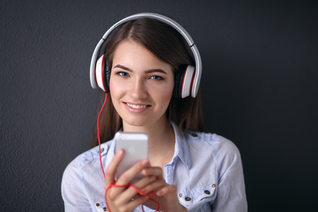 Smiling girl with headphones sitting on the floor near wallの写真素材