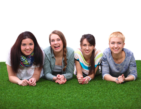 Four young women lying on green grassの写真素材