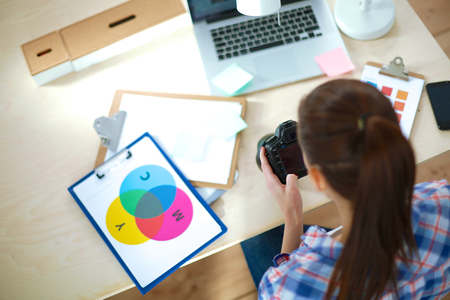 Female photographer sitting on the desk with laptopの写真素材