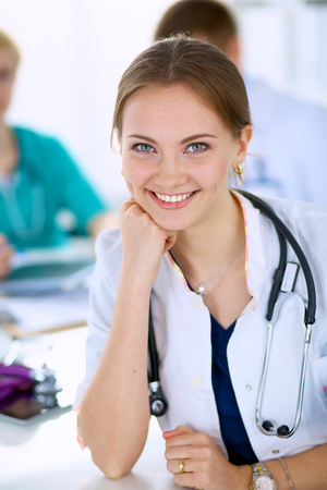 Beautiful young smiling female doctor sitting at the deskの写真素材