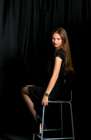 Beautiful woman sitting a chair, isolated on black backgroundの写真素材