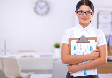 Portrait of a young woman working at office standing with folderの写真素材