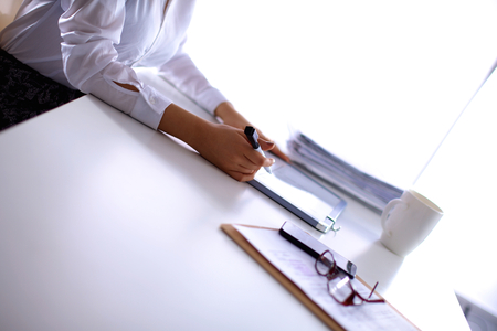 Woman with documents sitting on the desk, in officeの写真素材