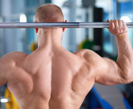 Bodybuilder standing with barbell in gym .の写真素材