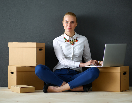 Woman sitting on the floor near a boxes  with laptop .の写真素材