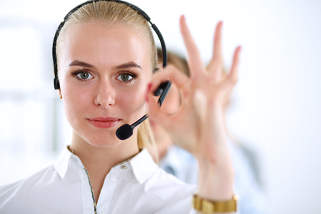 A smiling customer service girl showing ok, isolated on white backgroundの写真素材