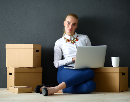 Woman sitting on the floor near a boxes  with laptop .の写真素材