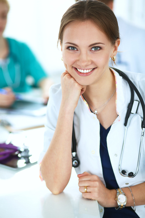 Beautiful young smiling female doctor sitting at the desk.の写真素材
